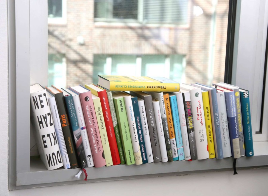 Ene Bücherreihe auf einem Fensterbrett.